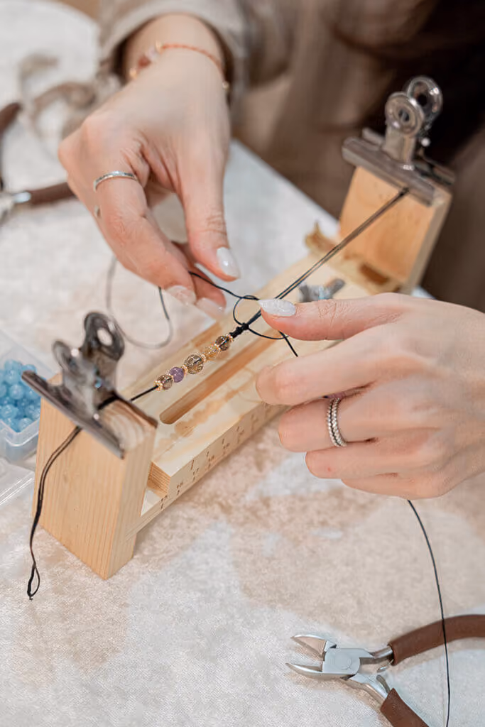 An artisan making a crystal bracelet with metal wire at a workbench